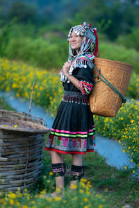 Woman holding umbrella while standing in basket on field