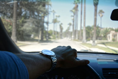 Cropped hand of man holding steering wheel in car