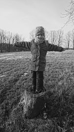 Portrait of boy standing on field against sky