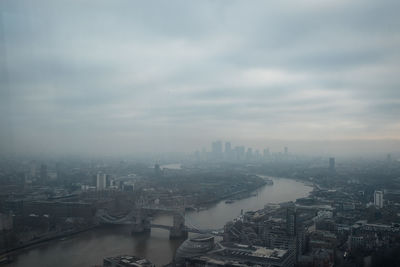 High angle view of city buildings against cloudy sky