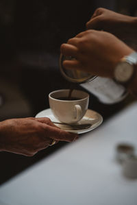 Midsection of man holding coffee cup on table