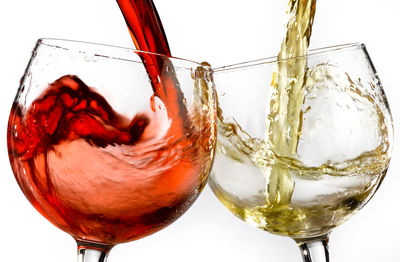 Close-up of wineglass on glass against white background