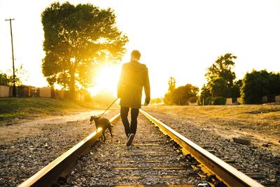 Silhouette of people walking on railroad track