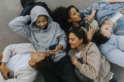 High angle view of smiling teenagers lying together and using their phones