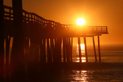 Silhouette pier over sea against sky during sunset