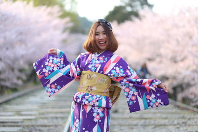 Portrait woman in kimono standing on footpath