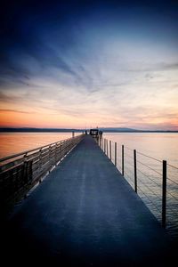 Surface level of pier on sea against sky during sunset