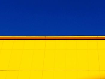 Low angle view of yellow wall against blue sky