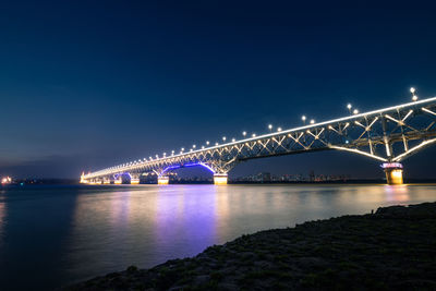 Low angle view of illuminated bridge over river at night