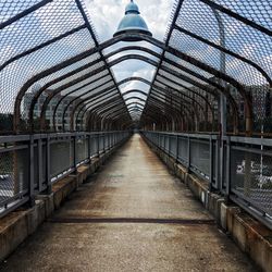 Empty footbridge amidst buildings