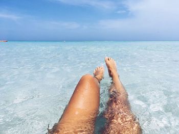 Low section of person on beach against sky