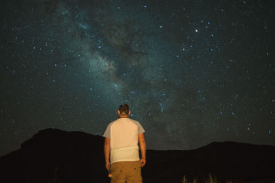 Rear view of man standing against star field at night