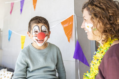 Mother painting her son's face like a clown