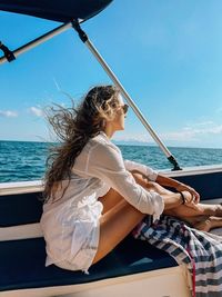 Portrait of young woman sitting at boat in the sea 