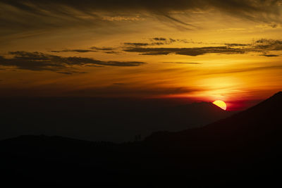 Scenic view of silhouette mountains against orange sky