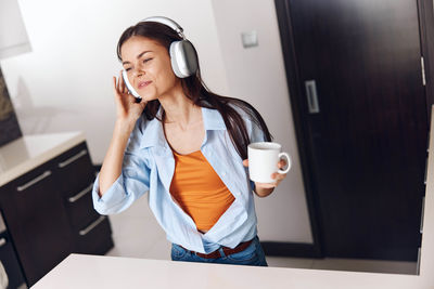 Portrait of young woman standing by window