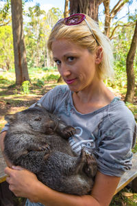 Woman holding wombat in forest