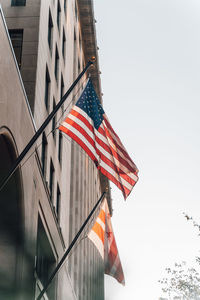Low angle view of flag against buildings against clear sky
