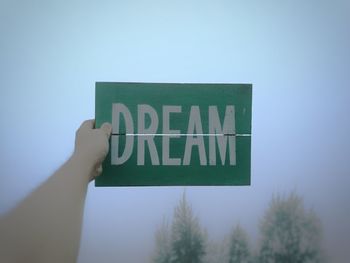 Cropped hand holding placard with dream text during foggy weather
