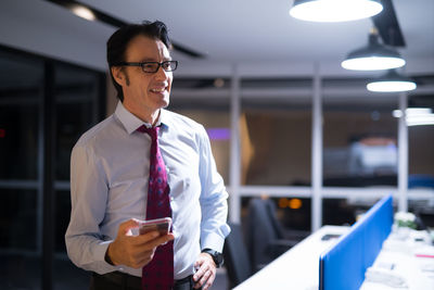 Businessman using mobile phone while standing at office