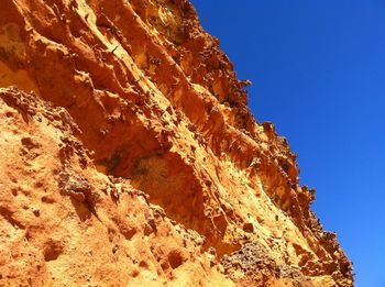 Low angle view of rock formation against clear blue sky