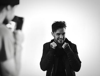 Young man smiling while standing against white background