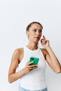 Portrait of smiling young woman using mobile phone against white background