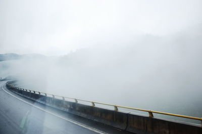 Bridge over road in foggy weather against sky