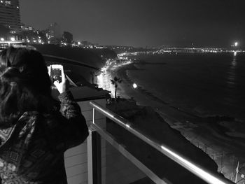 Rear view of woman looking at city at night