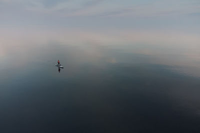 Evening walk on a sup board on the mirror surface of a calm sea. alone with nature