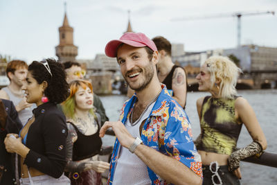 Portrait of smiling gay man wearing floral pattern and dancing with non-binary friends in city