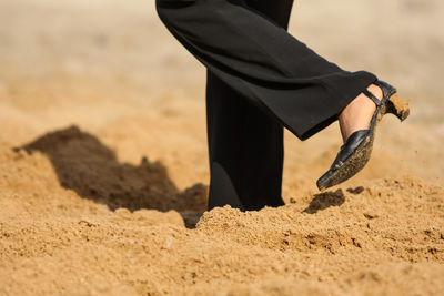 Low section of person walking in sand