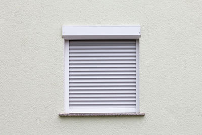 Closed window with a roller blind on a white wall