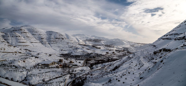 Scenic view of snowcapped mountains against cloudy sky