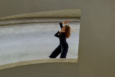 Side view of woman standing against wall