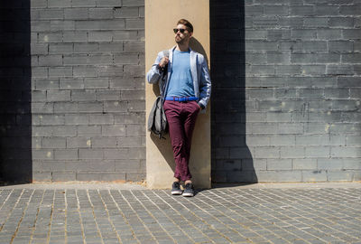 Full length of man wearing sunglasses standing against wall