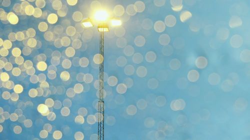 Defocused image of illuminated lights against sky