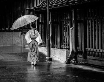Rear view of man holding woman with umbrella