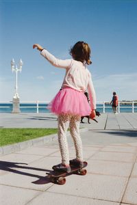 Girl skateboarding on promenade against sky