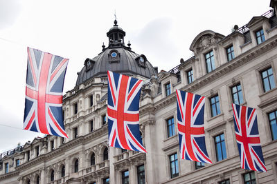 Low angle view of flags against buildings in city