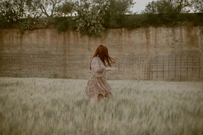 Rear view of woman walking on field