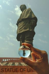 Low angle view of person holding camera against sky