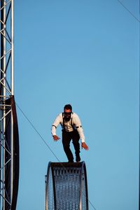 Low angle view of people standing against clear blue sky