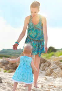 Full length of mother and daughter against sky