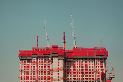 Low angle view of crane against building against clear sky