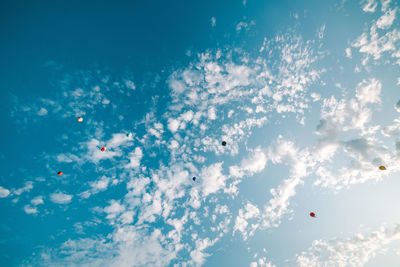 Low angle view of balloons flying against blue sky