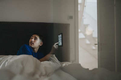 Boy controlling temperature of bedroom through digital tablet at modern home