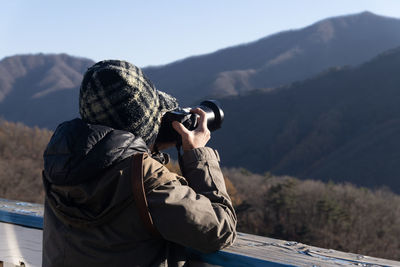 Rear view of a woman taking a photo in the mountain during autumn