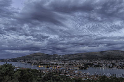 Scenic view of sea and town against cloudy sky