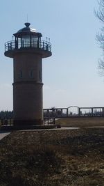 View of lighthouse by building against sky